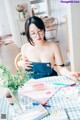 A woman sitting at a table with a bunch of art supplies.