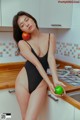 A woman in a black bathing suit holding an apple.