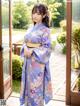 A woman in a blue kimono standing in front of a door.