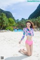 A woman in a pink bikini sitting on a beach.