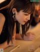 A woman sitting at a table with chopsticks and a glass of beer.