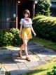 A woman in a yellow skirt and a white shirt is walking down a path.