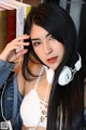 A woman with long black hair wearing white headphones.