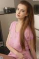 A woman in a pink dress sitting on a kitchen counter.