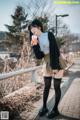 A woman standing on a sidewalk holding a cup of coffee.