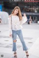 A woman in a white blouse and jeans posing for a picture.