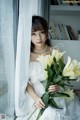 A woman in a white dress holding a bunch of white flowers.