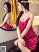 A woman in a red dress sitting in front of a mirror.