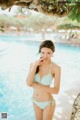 A woman in a blue bikini standing next to a pool.