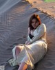 A woman sitting on top of a sandy beach.