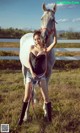 A woman standing next to a white horse in a field.