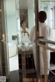 A woman in a white robe standing in front of a mirror.