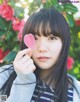 A young woman holding a pink heart in front of her face.